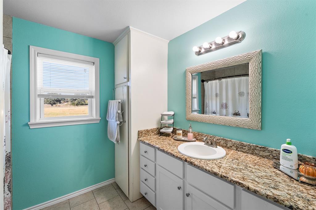 17215 Tarlton Road Mabank, TX 75147 - Photo 32 of 34 a bathroom with a granite countertop sink a mirror and a window