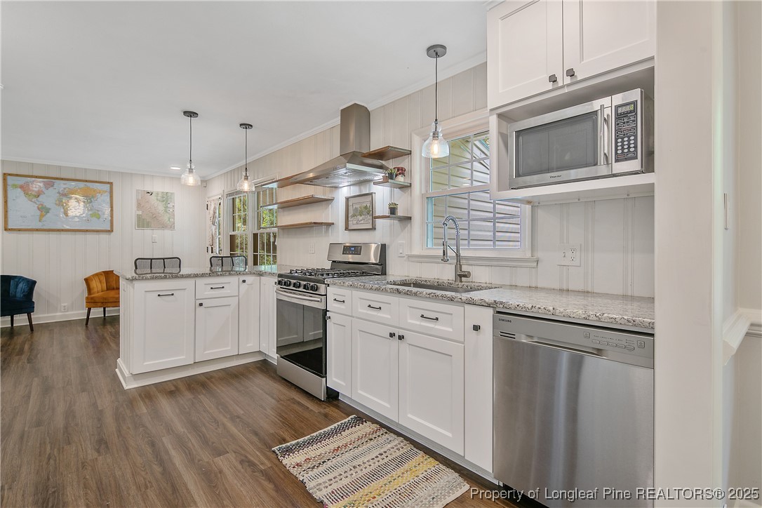 2615 Huntington Road Fayetteville, NC 28303 - Photo 17 of 47 a kitchen with stainless steel appliances granite countertop a dishwasher a stove and a wooden floor