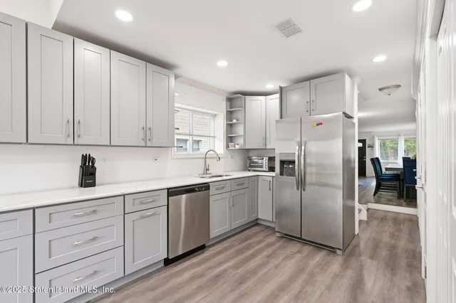 a kitchen with stainless steel appliances granite countertop a refrigerator sink and white cabinets