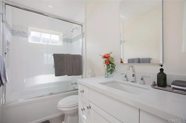 a bathroom with a granite countertop sink a toilet and a mirror