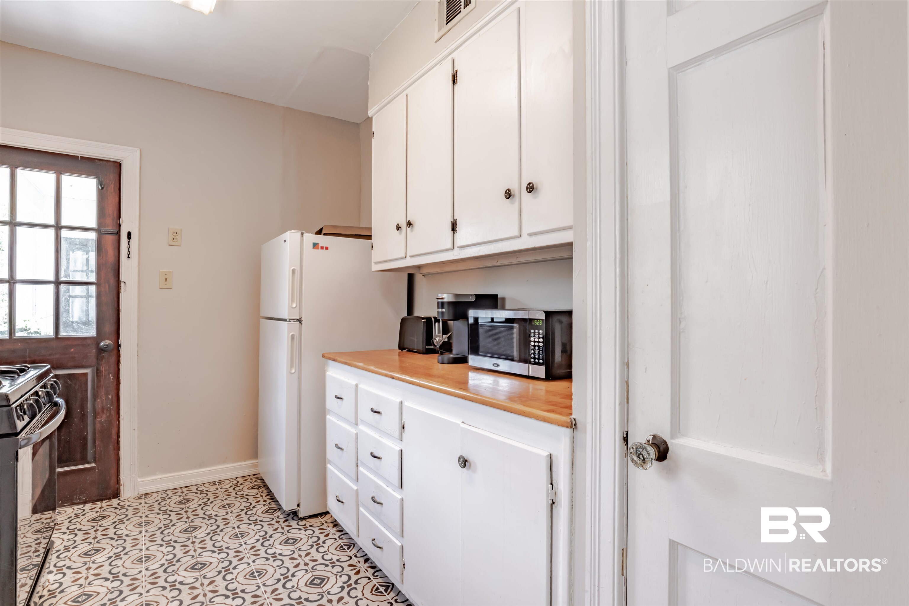 214 Upham Street, Unit 7C Mobile, AL 36607 - Photo 8 of 32 Kitchen with white cabinets, stainless steel microwave, freestanding refrigerator, and black range with gas stovetop