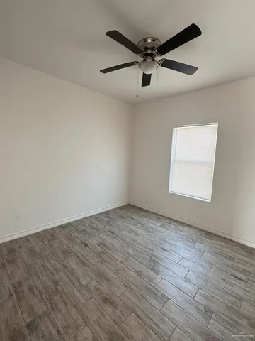 an empty room with wooden floor a ceiling fan and windows