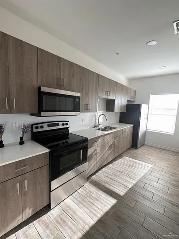 a kitchen with stainless steel appliances kitchen island granite countertop a sink dishwasher stove top oven and wooden cabinets