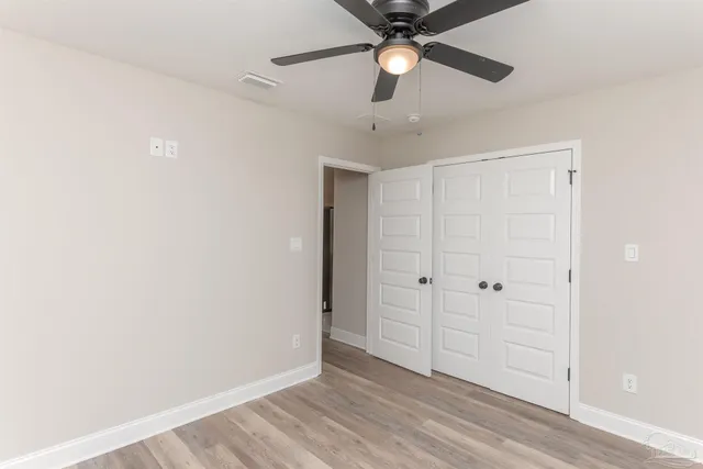 an empty room with a ceiling fan and wooden floor