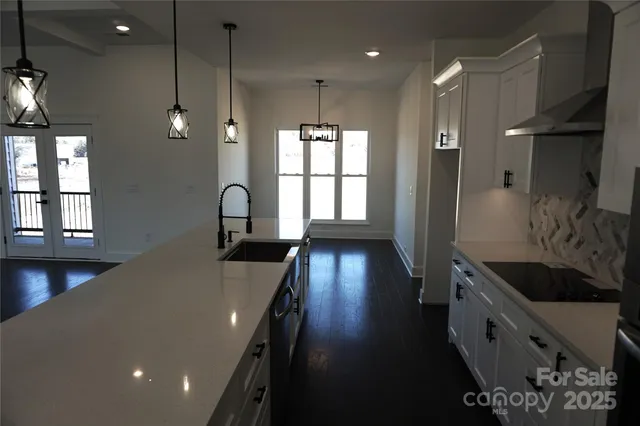 a kitchen with granite countertop a stove a sink a refrigerator and a window