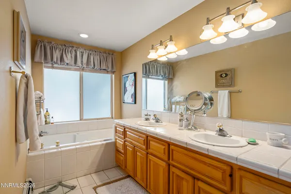 a spacious bathroom with a double vanity sink a mirror a bathtub and a window