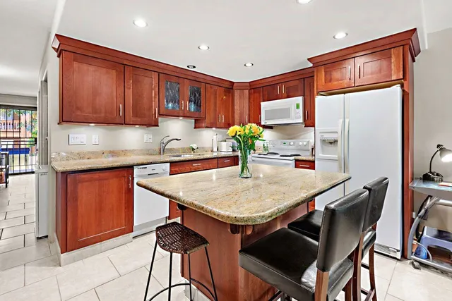 a kitchen with stainless steel appliances granite countertop a table chairs sink refrigerator and cabinets