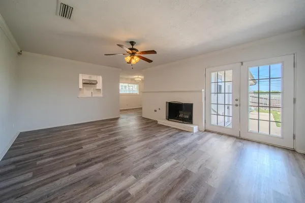 an empty room with wooden floor fireplace and windows