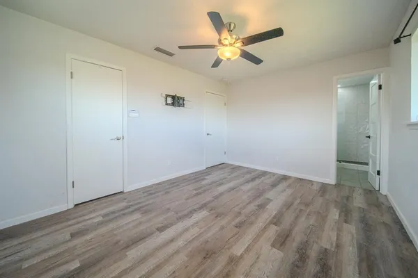 an empty room with wooden floor and a ceiling fan