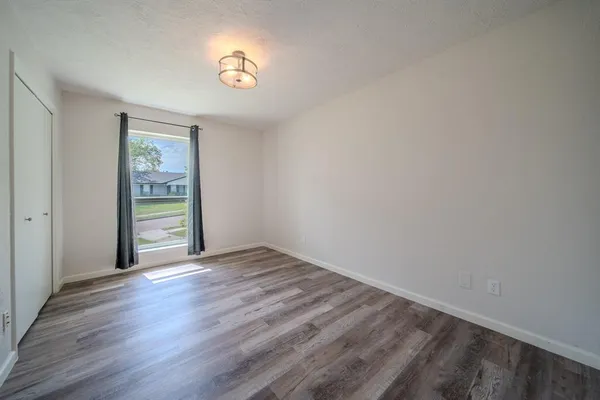 a view of an empty room with a window and wooden floor