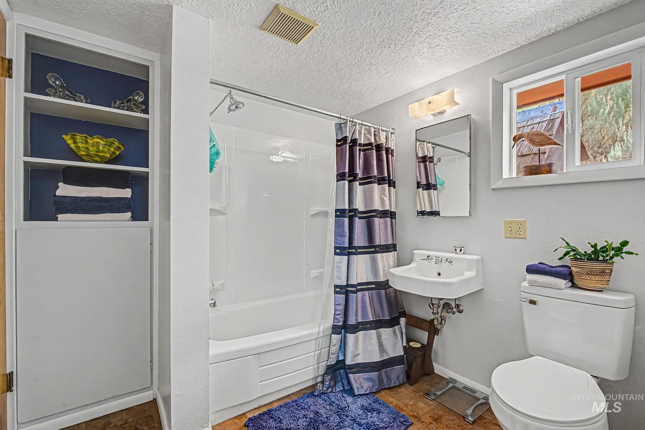 4311 Frozen Dog Road Emmett, ID 83617 - Photo 28 of 31 Bathroom featuring a white tub-shower combination, a wall-mounted sink, and a toilet