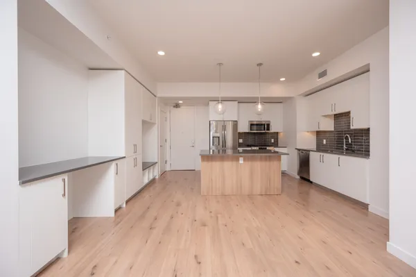 a large kitchen with stainless steel appliances wooden floors and white cabinets