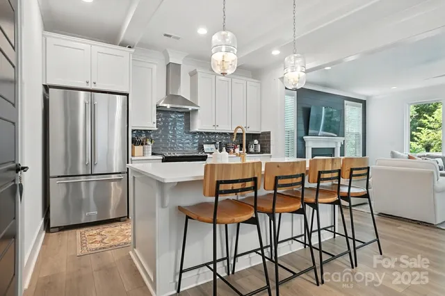 a kitchen with stainless steel appliances a dining table chairs refrigerator sink and cabinets