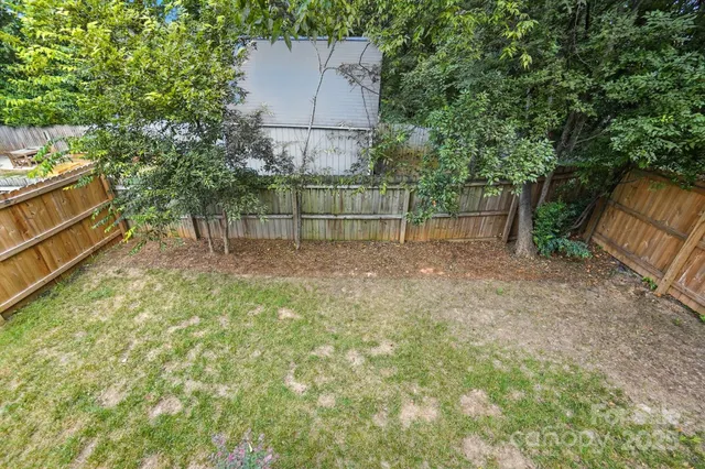 a view of backyard with small garden and wooden fence