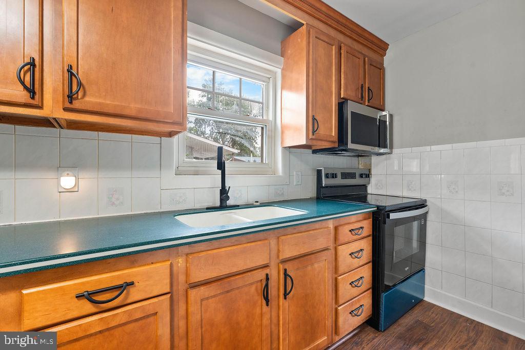 38 4th Street Laurel, MD 20707 - Photo 3 of 27 a kitchen with stainless steel appliances granite countertop a sink a stove and a microwave