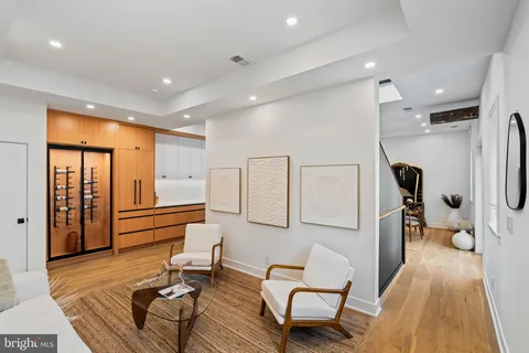 a view of a hallway to a livingroom with wooden floor a ceiling fan and windows