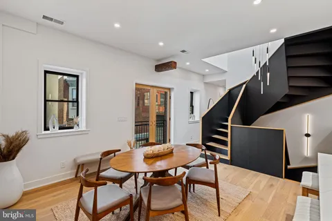 a kitchen with stainless steel appliances granite countertop a stove a sink a dining table and chairs with wooden floor