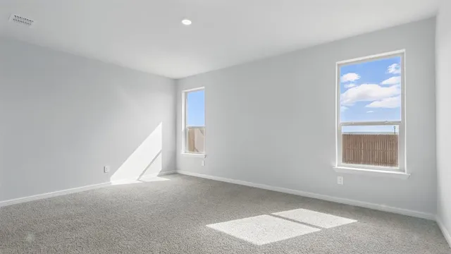 a view of an empty room and kitchen with wooden floor