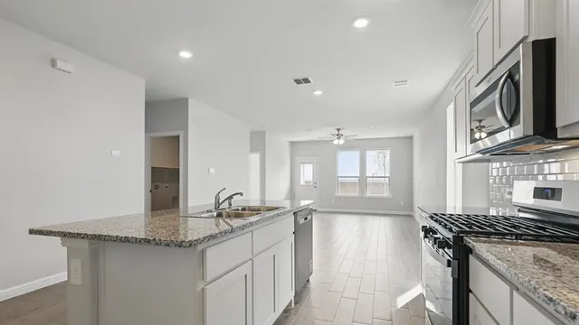 a view of a kitchen with a sink and dishwasher a refrigerator with wooden floor