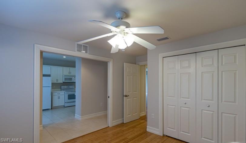 9113 Michael Circle, Unit 9 Naples, FL 34113 - Photo 12 of 28 wooden floor in an empty room with a chandelier fan