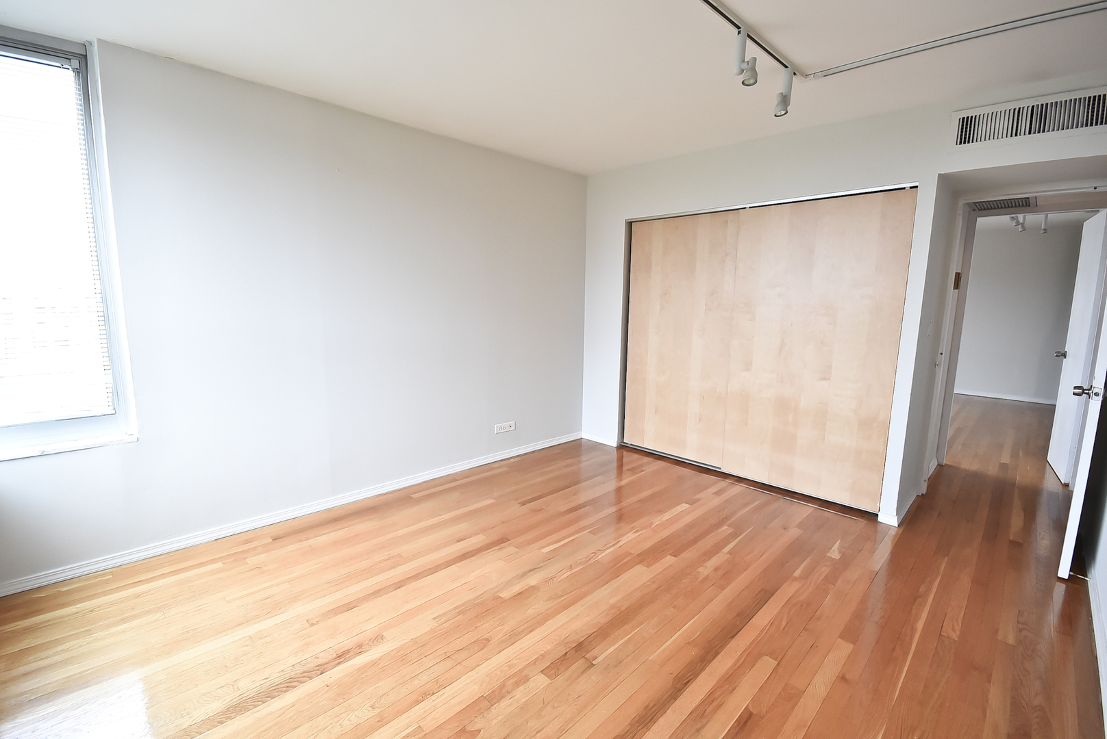 720 West Gordon Terrace, Unit 8L Chicago, IL 60613 - Photo 12 of 15 a view of an empty room with wooden floor and a window
