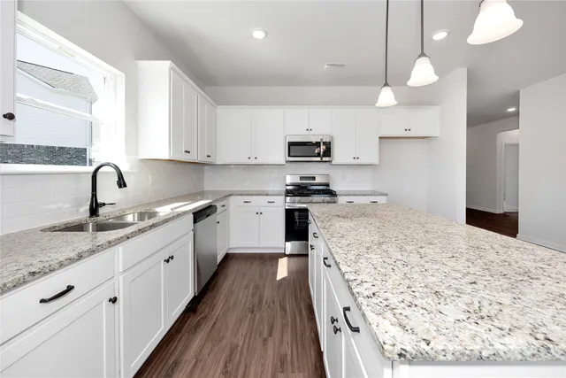 a large kitchen with kitchen island a sink a counter top space stainless steel appliances and cabinets