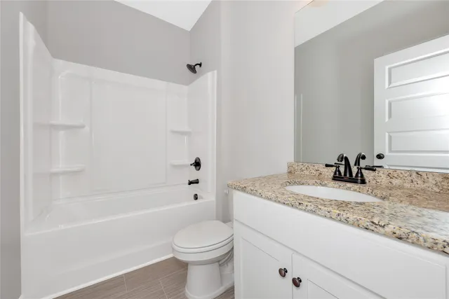 a bathroom with a granite countertop sink toilet and bathtub