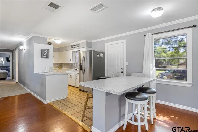 a kitchen with a table chairs refrigerator and wooden floor