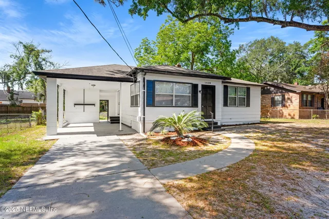 a front view of a house with a yard and potted plants