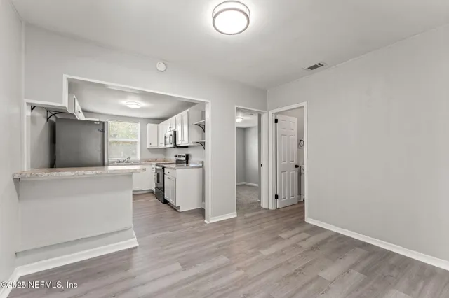 a view of a kitchen with wooden floor and electronic appliances
