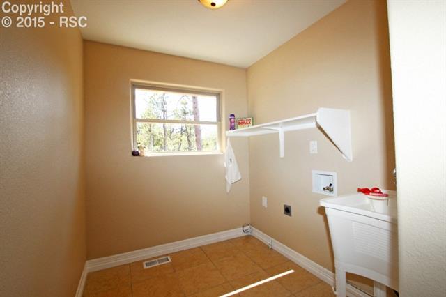 11420 Teachout Road Colorado Springs, CO 80908 - Photo 23 of 36 Large well-lighted laundry room with shelves and sink.