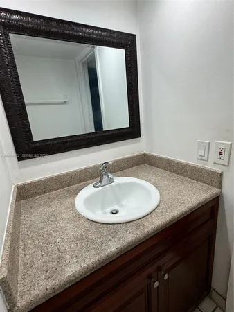a bathroom with a granite countertop sink and a mirror