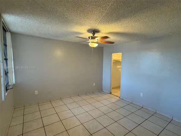 a view of an empty room and chandelier fan