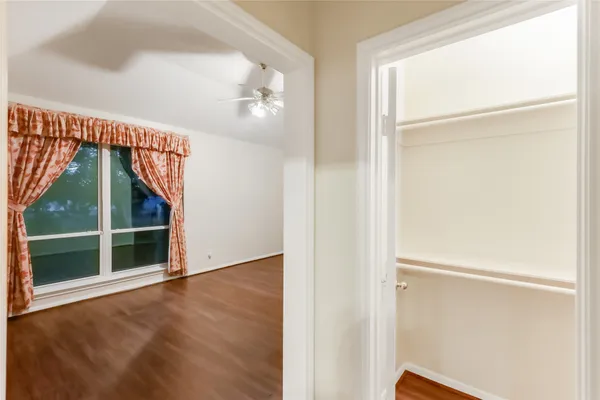 an empty room with wooden floor fan and windows