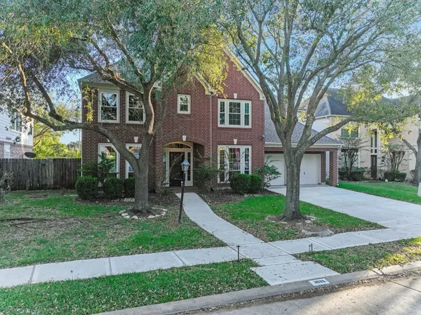 a front view of a house with a garden and trees