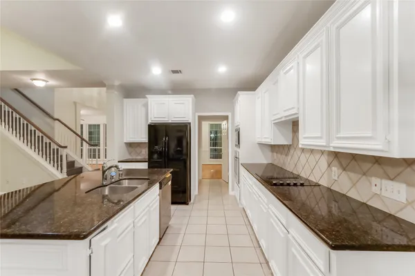 a large kitchen with granite countertop a sink and a stove top oven