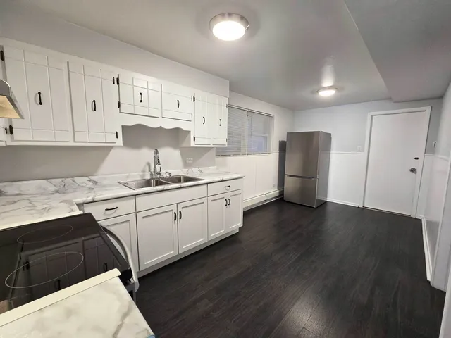 a kitchen with wooden floor and electronic appliances
