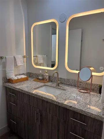 a bathroom with a granite countertop sink and a mirror