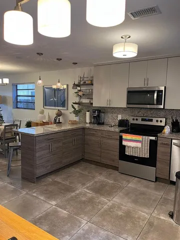 a kitchen with stainless steel appliances granite countertop a stove a sink and a refrigerator