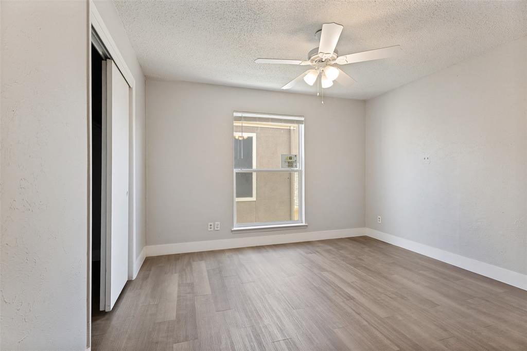 5522 Boca Raton Boulevard, Unit 404 Fort Worth, TX 76112 - Photo 9 of 12 Room featuring wood-finish flooring, a ceiling fan with integrated lighting, a double-hung window, and sliding closet doors