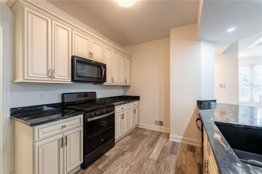 234 Adams Pointe Boulevard, Unit 2 Mars, PA 16046 - Photo 12 of 36 a kitchen with granite countertop a stove a sink and a microwave