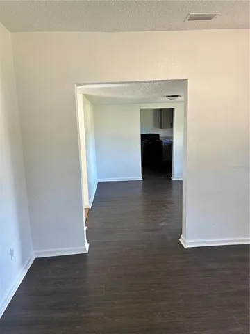 a view of an empty room with wooden floor and closet