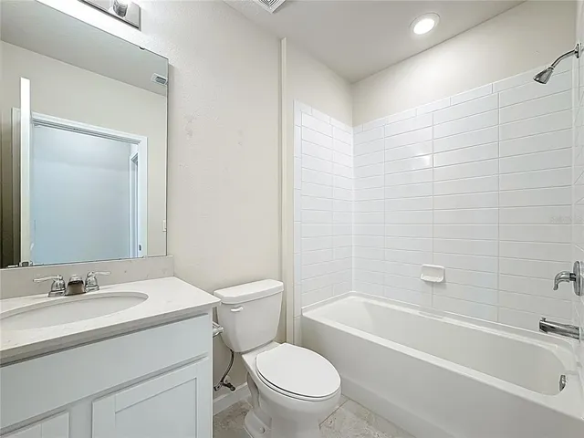a bathroom with a granite countertop toilet a sink and a bathtub