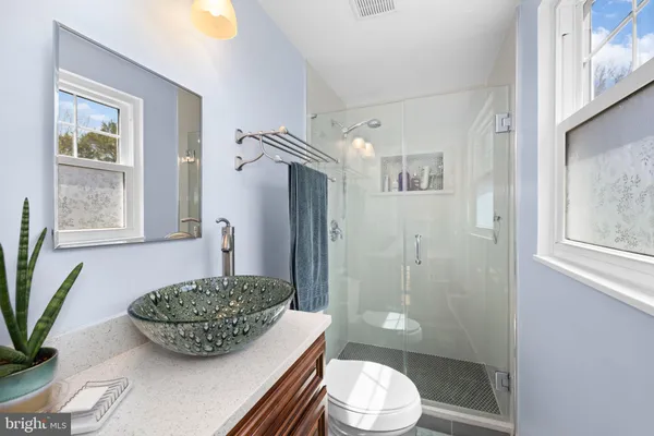 a bathroom with a granite countertop sink toilet a mirror and shower