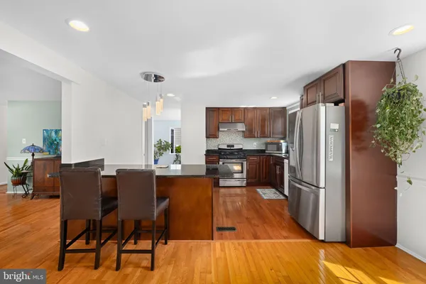 a kitchen with stainless steel appliances a refrigerator a stove a dining table and chairs