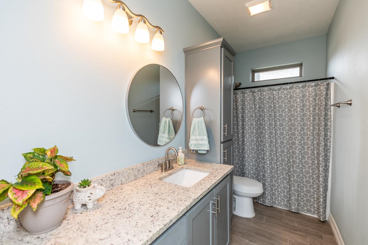 314 Long Leaf Street Silsbee, TX 77656 - Photo 22 of 31 a bathroom with a granite countertop sink a toilet and a mirror