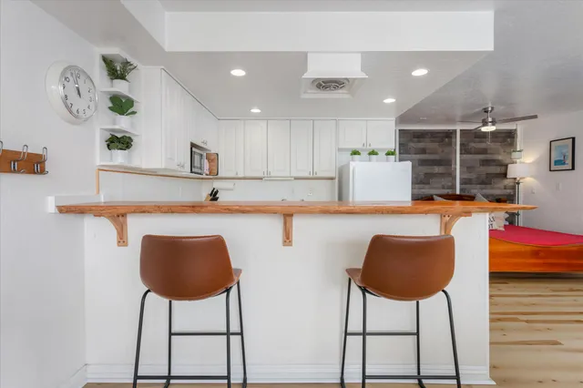 a kitchen with stainless steel appliances granite countertop a dining table chairs and a refrigerator