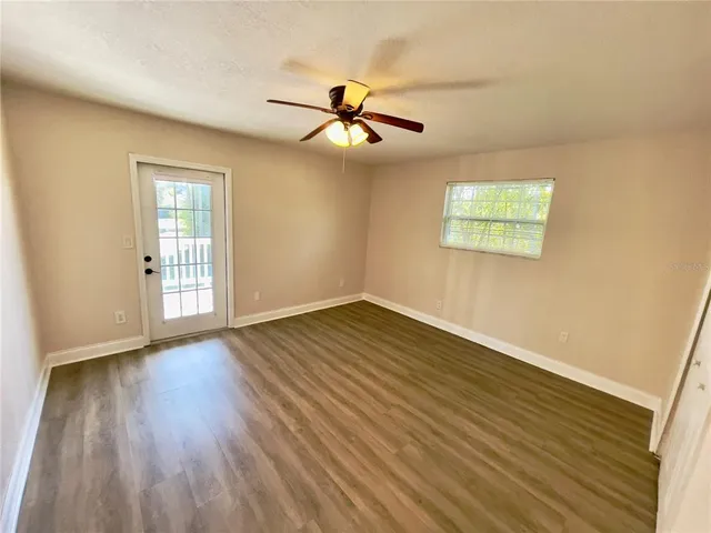 an empty room with wooden floor ceiling fan and windows