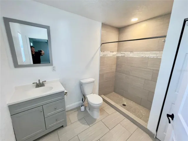 a bathroom with a shower sink vanity and toilet