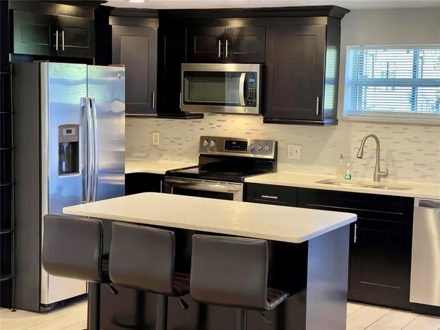 a kitchen with stainless steel appliances a table chairs microwave and refrigerator